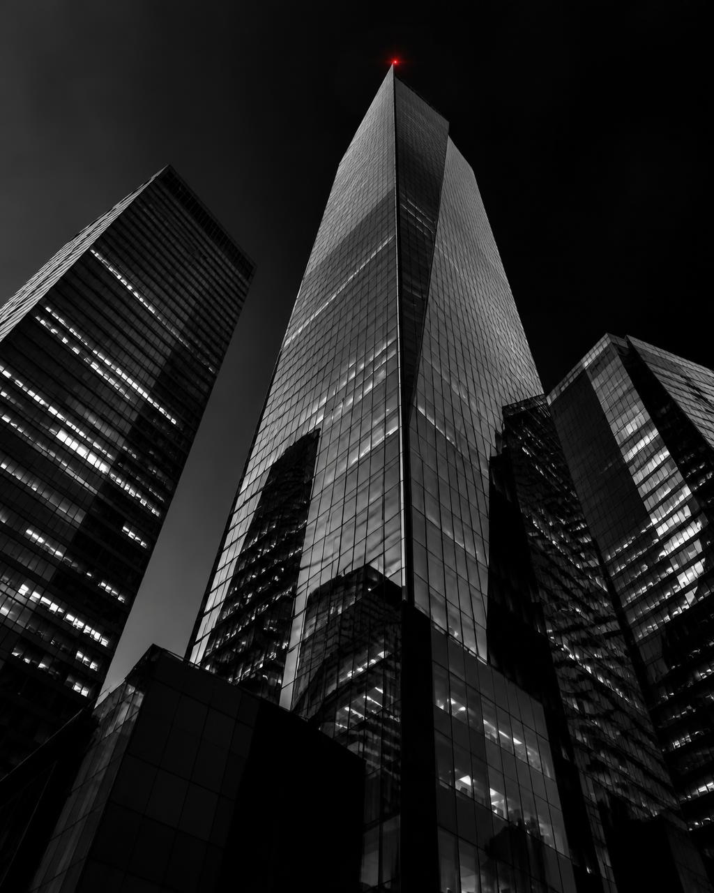 Black and white skyscrapers at night with a single red light